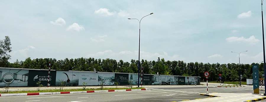 Hàng rào công trường The Habitat Grand tại vòng xoay A1, Thành phố mới Bình Dương, có bảng tên dự án và logo VSIP – Sembcorp, chụp tháng 7/2026